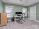 A bright office space features a modern desk setup with dual monitors and ample natural light from two windows at 4008 Widgeon Way, Waxhaw, NC 28173