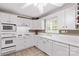 Bright kitchen featuring white appliances, white cabinets, and tile countertops and backsplash at 422 Wildwood Dr, Salisbury, NC 28146