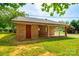 Rear view of a brick home featuring a covered porch, manicured lawn and mature trees at 862 Eastwood Dr, Rock Hill, SC 29730