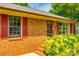 Close up on the brick facade, red shutters, and manicured greenery of this charming home at 862 Eastwood Dr, Rock Hill, SC 29730
