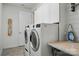 Clean laundry room boasts a washer and dryer, storage cabinets, and modern appliances at 9565 Horsebit Ln, Concord, NC 28027