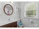 Bathroom with window, round mirror, and storage cabinet at 1007 Doby Springs Dr, Charlotte, NC 28262