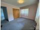 Bedroom with pink walls, carpet flooring, a closet with wooden doors, and a window at 1012 Burrage Ne Rd, Concord, NC 28025
