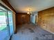 Spacious living room with wood paneling, carpet flooring, and sliding glass doors to the outside patio at 1012 Burrage Ne Rd, Concord, NC 28025