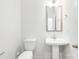 Clean, well-lit bathroom with a pedestal sink, a modern mirror, and a toilet at 1141 Thayer Glen Ct, Charlotte, NC 28213