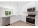 Modern kitchen featuring white cabinets, stainless steel appliances, marble backsplash, and hardwood floors at 1141 Thayer Glen Ct, Charlotte, NC 28213