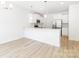 Bright, open-concept kitchen featuring white cabinets, a breakfast bar, stainless steel appliances, and hardwood floors at 1141 Thayer Glen Ct, Charlotte, NC 28213