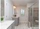 This is a bathroom with a glass door shower, window, and dual vanity with modern tile floors at 12214 Ardrey Park Dr, Charlotte, NC 28277