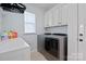 A bright laundry room is equipped with a washer, dryer, and storage cabinets at 13115 Union Square Dr, Huntersville, NC 28078