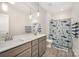 Well-lit bathroom with double sinks, stylish tile, and a shower with a patterned curtain at 1390 Cedardale Ln, Denver, NC 28037