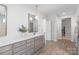 Bright bathroom with dual sinks, framed mirrors, wood-look tile, and access to a large closet at 1390 Cedardale Ln, Denver, NC 28037