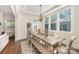 Sunlit dining area featuring a rustic table, bench seating, and large windows overlooking the backyard at 1390 Cedardale Ln, Denver, NC 28037