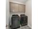Functional laundry room includes modern washer and dryer, patterned floor tiles, and gray cabinetry at 1390 Cedardale Ln, Denver, NC 28037
