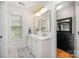 Modern bathroom featuring double sinks, gold fixtures, a window, and a walk-in closet for ample storage at 14457 Adair Manor Ct, Charlotte, NC 28277