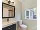 Bathroom with vanity, toilet, window, and black framed mirror at 1620 Matthews Dr, Rock Hill, SC 29732