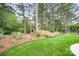 Backyard oasis featuring lush greenery, mature trees, and decorative stone landscaping at 17408 Summer Place Dr, Cornelius, NC 28031