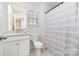 Clean bathroom features a white vanity, toilet, and bathtub with gray striped shower curtain at 17502 Snug Harbor Rd, Charlotte, NC 28278