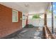 Covered carport featuring a red door, brick wall, and white gate, providing sheltered parking and access to the backyard at 218 N Bost St, Statesville, NC 28677