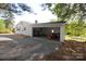 Home's backyard featuring light siding, a gravel driveway, a carport, and mature trees at 306 E Burnsville St, Wadesboro, NC 28170