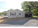 Home exterior featuring light siding, a gravel driveway, and a convenient carport with space for equipment and vehicles at 306 E Burnsville St, Wadesboro, NC 28170