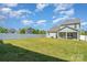 Large fenced backyard featuring green lawn, houses, and a covered patio with seating, perfect for outdoor gatherings at 4406 Huntley Glen Dr, Pineville, NC 28134