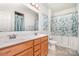 Bathroom featuring double vanity, light-colored tile, and shower with light-leaf patterned shower curtain at 4406 Huntley Glen Dr, Pineville, NC 28134