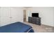 Bright bedroom featuring neutral walls, carpet flooring, and a gray dresser below a modern, wall-mounted television at 4406 Huntley Glen Dr, Pineville, NC 28134