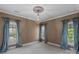 This is a bedroom featuring two large windows, a decorative chandelier, and soft, neutral paint at 4465 3Rd Nw St, Hickory, NC 28601