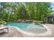 Beautiful in-ground pool featuring a tanning deck, integrated spa, stone surround, and lush landscaping at 4561 Walden Pond Trwy, Concord, NC 28025