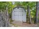 Outdoor storage shed in a wooded setting, featuring double doors and a simple design at 4561 Walden Pond Trwy, Concord, NC 28025