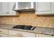 Close-up of a gas range with stainless steel hood and decorative backsplash in a modern kitchen at 648 Revival Row, Fort Mill, SC 29708