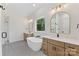 Bright bathroom with soaking tub between two wooden vanity cabinets and updated lighting fixtures at 6511 Rehobeth Rd, Waxhaw, NC 28173