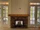 Close up of stone fireplace with wood mantel and white doors on either side of the fireplace at 6511 Rehobeth Rd, Waxhaw, NC 28173