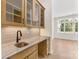 Kitchen area with marble countertops, sink, tile backsplash, and light wood cabinets with glass doors at 6511 Rehobeth Rd, Waxhaw, NC 28173
