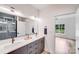Modern bathroom featuring double sinks, sleek gray cabinets, and stylish light fixtures, with an adjacent tiled shower at 6907 Lancaster Hwy, Waxhaw, NC 28173