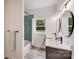 Updated bathroom with double sinks, round mirrors and green tiled shower and tub at 6907 Lancaster Hwy, Waxhaw, NC 28173