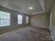 Spacious bedroom with plush carpeting, tray ceiling, and natural light at 8323 Carolina Laurel Ct, Charlotte, NC 28215