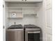 Convenient laundry room featuring silver washer and dryer units in a closet with shelves at 879 Park Slope Dr, Charlotte, NC 28209