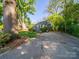 Charming gray home nestled among mature trees with a spacious cracked driveway at 1142 Mona Dr, Charlotte, NC 28206