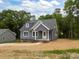 New home featuring a gray siding, brick foundation, and an inviting covered porch at 130B Springway Dr, Kannapolis, NC 28081