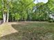 Large, grassy backyard surrounded by mature trees and a black metal fence at 1409 Bloomsberry Ln, Waxhaw, NC 28173
