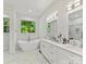 Bright bathroom featuring a standalone tub, dual sinks, and a large window with a wooded view at 1409 Bloomsberry Ln, Waxhaw, NC 28173