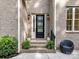 Charming front door with sidelights, complemented by potted plants and a cozy chair at 1409 Bloomsberry Ln, Waxhaw, NC 28173