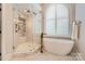 Bathroom featuring a glass shower and large tub with natural light at 14131 Lea Point Ct, Huntersville, NC 28078