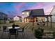 Beautiful backyard at dusk featuring a patio, outdoor dining set, and well-manicured lawn, perfect for evening relaxation at 1543 Ab Moore Jr Dr, Indian Trail, NC 28079