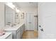 Bathroom featuring double sinks, a large mirror, linen closet, and a glass enclosed shower with neutral color palette at 1543 Ab Moore Jr Dr, Indian Trail, NC 28079