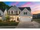 Charming two-story home featuring a manicured lawn, gray siding, black shutters and a two car garage under a vibrant sunset at 1543 Ab Moore Jr Dr, Indian Trail, NC 28079