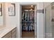 View of a walk-in closet, seen from the bathroom; the closet is full of hanging clothing on metal racks at 1543 Ab Moore Jr Dr, Indian Trail, NC 28079