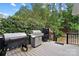 Outdoor cooking area on back deck with stainless grill, smoker, and Traeger, surrounded by lush green plants at 16532 Flintrock Falls Ln, Charlotte, NC 28278