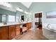 Spacious bathroom featuring dual vanities, wood cabinets, and a separate tub area at 16532 Flintrock Falls Ln, Charlotte, NC 28278